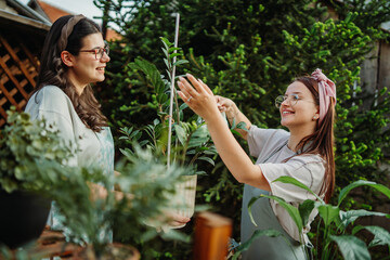 Two female friends or sisters taking care of plants with water can and mister	
