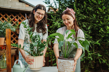 Two female friends or sisters taking care of plants with water can and mister	
