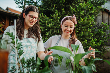 Two female friends or sisters taking care of plants with water can and mister	
