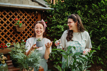 Two female friends or sisters taking care of plants with water can and mister	
