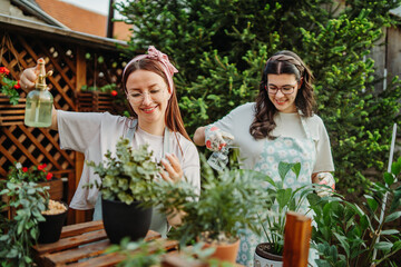 Two female friends or sisters taking care of plants with water can and mister	
