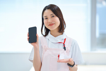 スマートフォンを持つ白衣とエプロン姿の女性