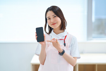 スマートフォンを持つ白衣とエプロン姿の女性