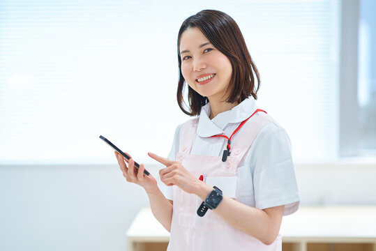 スマートフォンを持つ白衣とエプロン姿の女性