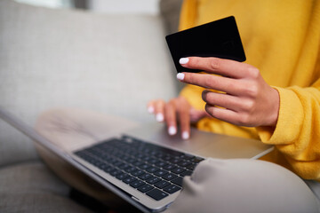 Close-Up of a Person Holding a Credit Card and Typing on a Laptop at Home