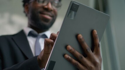 Close up African American happy smiling business man in office using graphics digital tablet computer device smile carefree ethnic male businessman guy worker browsing touchscreen online work internet - Powered by Adobe