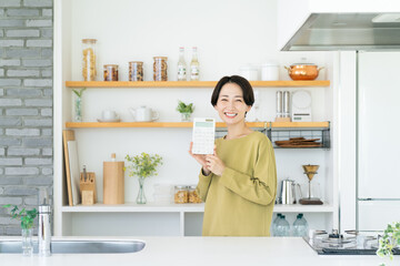 キッチンで電卓を持つミドルの女性