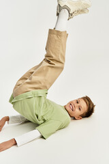 Joyful little boy showcasing playful spirit in vibrant attire while lying on a clean backdrop