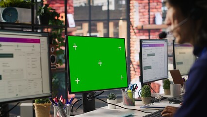 Call center worker solving customers issues using green screen PC. Customer support staff member in front of chroma key computer display using headset to talk with clients, camera A