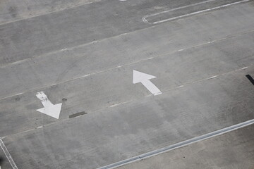 Sign two opposite white straight arrow show direction on gray asphalt and concrete forward and backward 