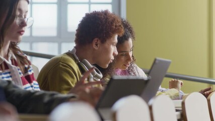 Handheld shot of group of diverse collegemates using digital devices during lecture in auditorium - Powered by Adobe