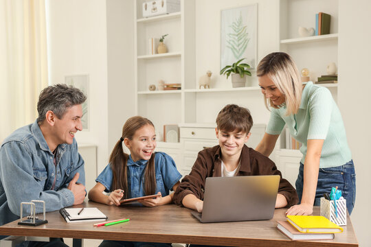 Happy parents and their children doing homework at table indoors - Powered by Adobe