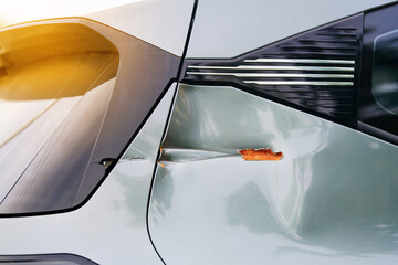 Damaged car rear panel, chipped paint, surface rust, deep dent near the trunk lid caused by minor collision and exposure to the elements. Broken decorative plastic panels of trunk lid. Selective focus