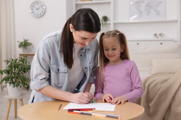 Fototapeta premium Mother teaching her daughter to draw at table indoors