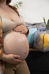Pregnant woman stroke big belly and collects a bag in the hospital at home. Future mom at 9 months...
