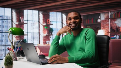 African american remote worker solving his daily freelancing tasks on laptop, working in relaxation...