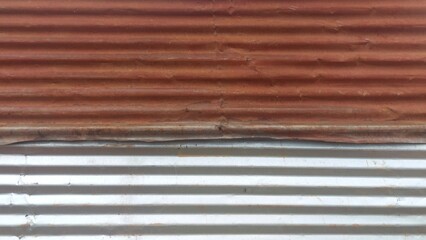 Rusty corrugated iron sheet meeting new metal sheet in construction site