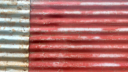 Red and grey corrugated iron sheet metal forms a weathered construction fence background