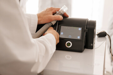 Medical CPAP Humidifier Setup: Doctor Connecting Hose to Sleep Apnea Machine on White Table, Healthcare Concept