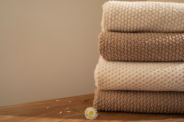 Stack of beige towels in modern aesthetic interior. Fabric bathroom accessories for hygiene, spa and skin care.