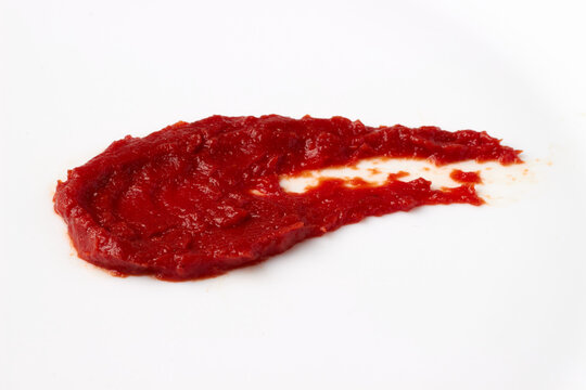 red blob of tomato ketchup paste smeared on white table. isolated on white background