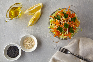 coleslaw of cabbage and carrots with sesame seeds and lemon-oil dressing on a concrete table