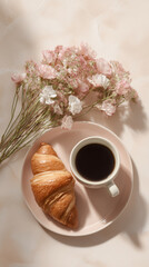 Cup of coffee and croissant wit brunch of pastel flowers on cozy morning sunlight 