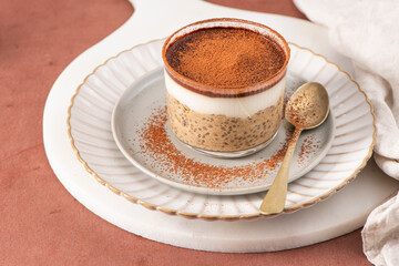 Chia pudding dessert with a layer of creamy yogurt and a dusting of cocoa powder, served in a glass...
