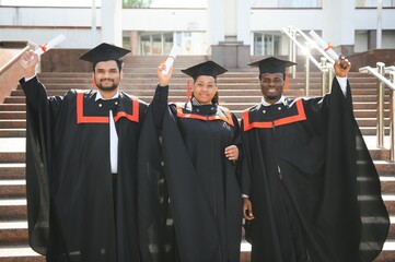 education, graduation and people concept - group of happy international students in mortar boards...