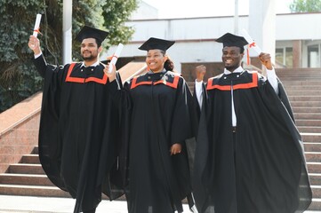 education, graduation and people concept - group of happy international students in mortar boards...