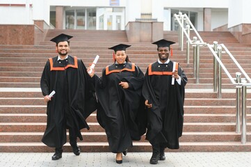 Diverse international students with diplomas attending graduation ceremony, happy multiracial group...