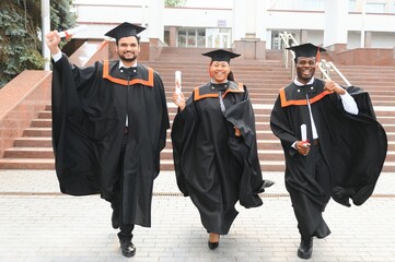 Diverse international students with diplomas attending graduation ceremony, happy multiracial group...