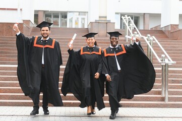 Group of multiracial graduate students with diplomas on university background