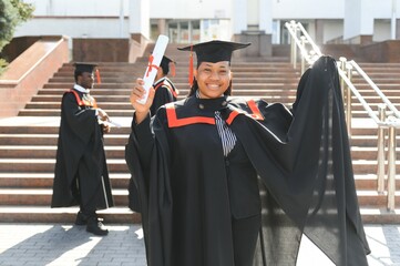 pretty african female college graduate at graduation with classmates