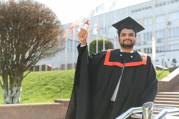 Handsome indian graduate in graduation glow with diploma