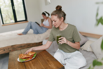 Active middle age woman enjoying a healthy green smoothie and a fresh croissant, embracing wellness...