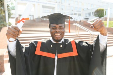 I have finally graduated. Happy young African man in graduation gowns holding diploma