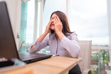 Indonesian southeast asian businesswoman experiencing stress and burnout while working on laptop in...