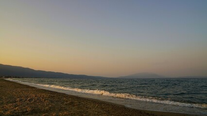 Golden sunset over the sea with gentle waves on a deserted beach