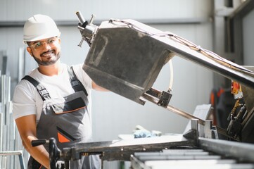 Portrait of cheerful young worker wearing hardhat at modern factory