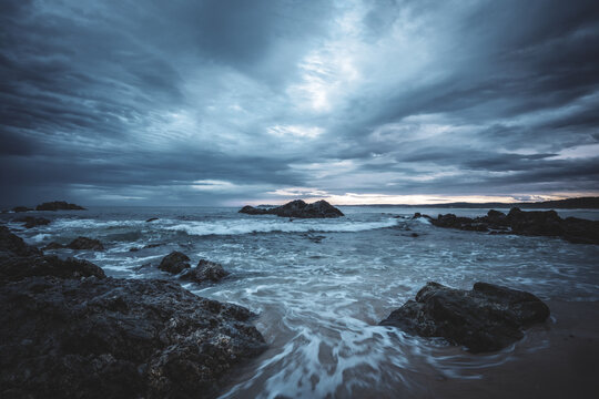 dark storm clouds over rocks on ocean shore on south coast