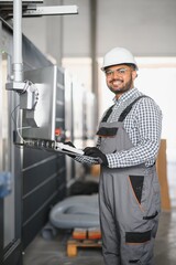 Young Indian male engineer wearing safety workwear standing in the factory