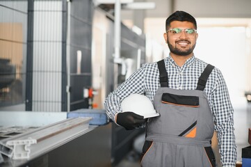 Operator of machine. Industrial worker indoors in factory. Young technician in white hard hat