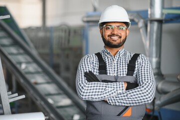 Young Indian male engineer wearing safety workwear standing in the factory