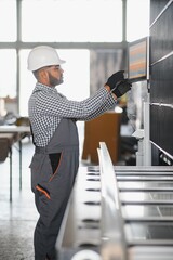 Operator of machine. Industrial worker indoors in factory. Young technician in white hard hat