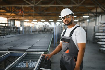 Operator of machine. Industrial worker indoors in factory. Young technician in white hard hat