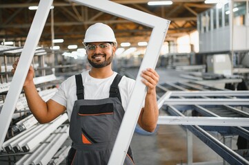 Young Indian male engineer wearing safety workwear standing in the factory