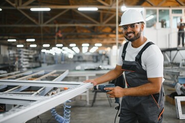 Operator of machine. Industrial worker indoors in factory. Young technician in white hard hat