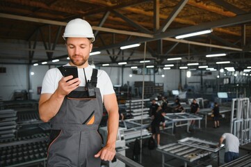 A young male engineer inspects the production of plastic window frames