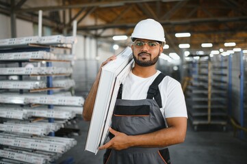 Smiling and happy indian employee. Industrial worker indoors in factory. Young technician with...